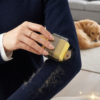Hand of a woman using Bepety Washable Pet Hair Roller on a dark navy sweater to remove dog hair